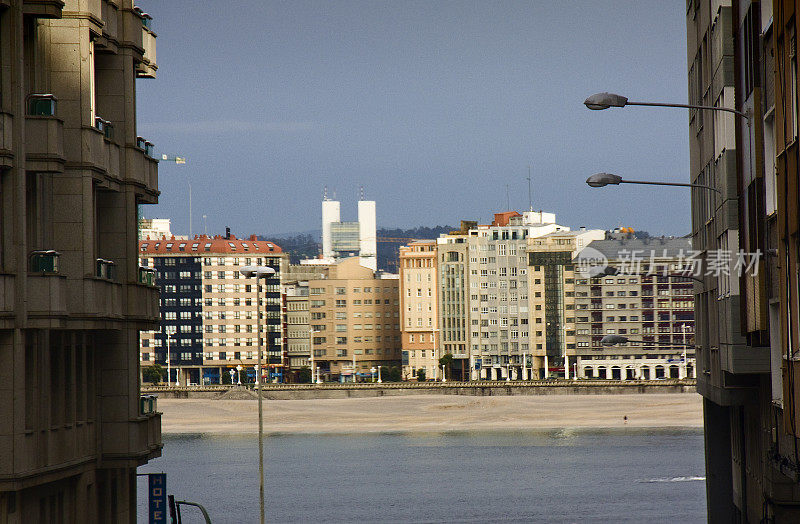 A Coruña  cityscape seen from narrow city street, seascape, beach and waterfront apartment buildings.